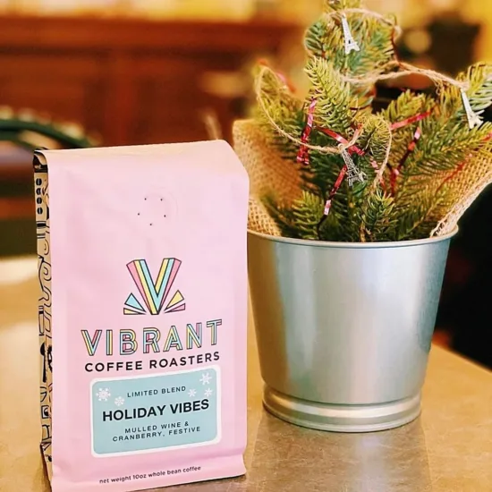 Vibrant's pink seasonal coffee bag and a holiday decoration of greenery.