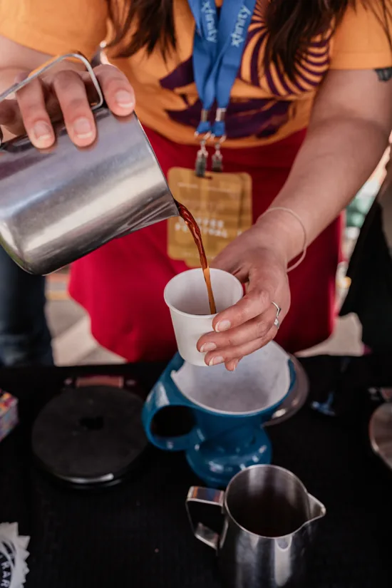 A vendor pours coffee into a paper cup.