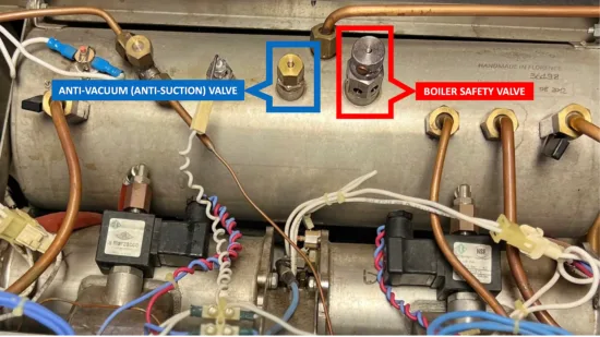Inside an espresso machine. On top of a metal chamber are highlighted two valves, one anti-vaccuum or anti-suction valve, one boiler safety valve.