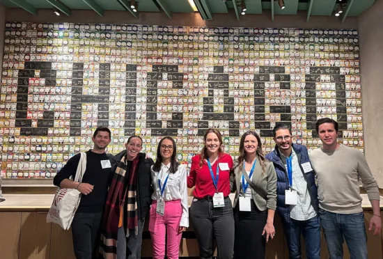 Group photo of seven people at NCA Next Gen in Chicago, in front of a wall spelling out Chicago in small cards.