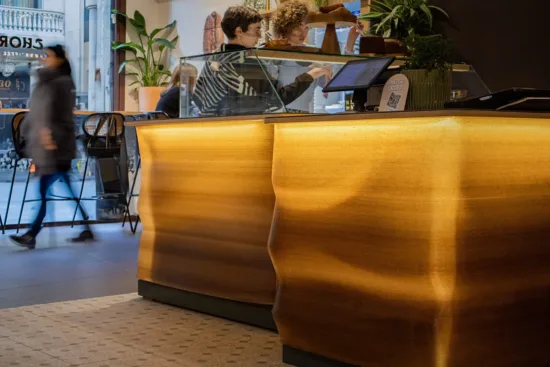 A wavy-patterned 3-d printed amber colored bar, with a flat top and glass case.