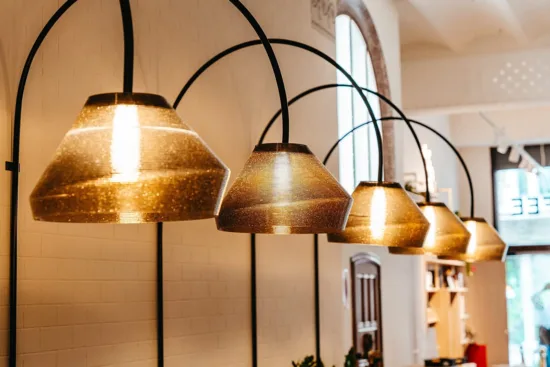 Amber lamps hang from black metal arches along the wall.