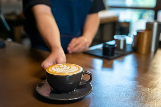 A barista presents a latte with latte art.