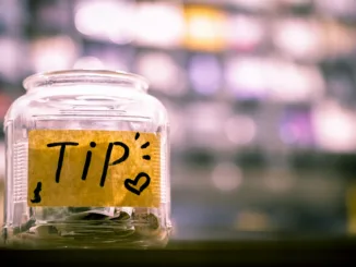 A clear glass tip jar on a café counter.
