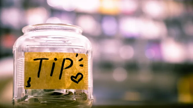 A clear glass tip jar on a café counter.