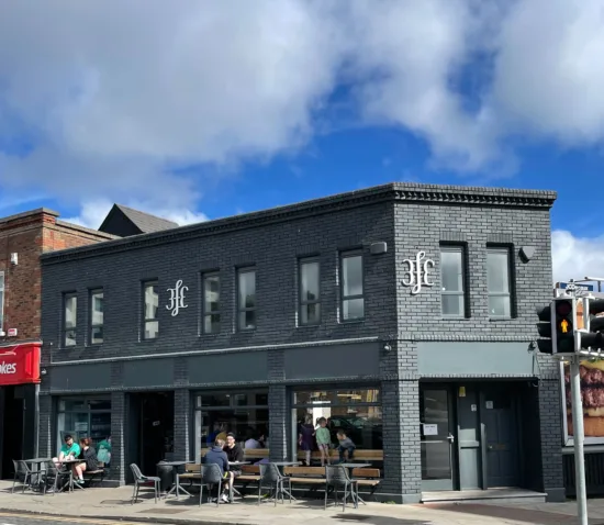 Outside a 3fe location with gray exterior and tables lined up outside. 