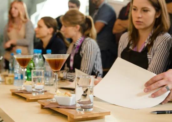 People in aprons sit at a table with coffee cocktails.