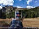 A person holds a coffee cup with the Colorado state flag on it in front of mountains.