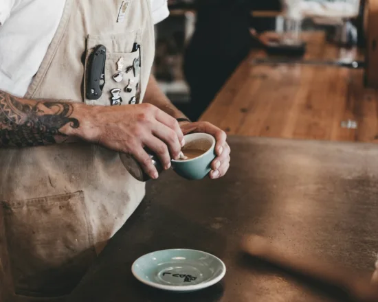 A person pours latte art in to a coffee cup.