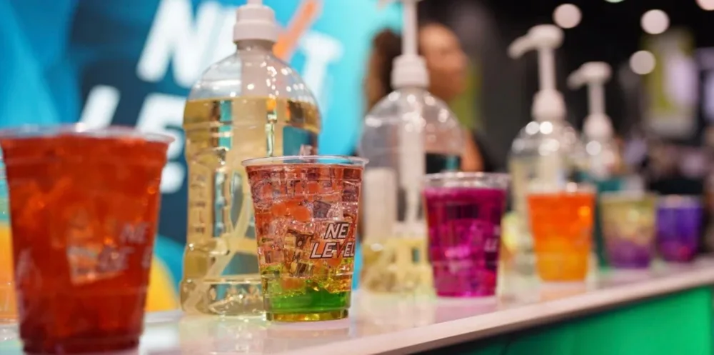 A line of Next Level Energy drinks on a bar with bottles of concentrated behind them.