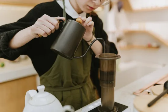 A barista pours water into an AeroPress.