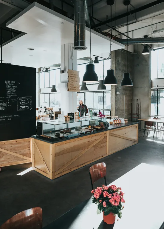 Inside a spacious cafe with chalkboard walls, black pendant lights, and a glass pastry case.