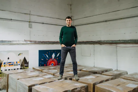 Colin stands on top of wrapped coffee crates in a warehouse.