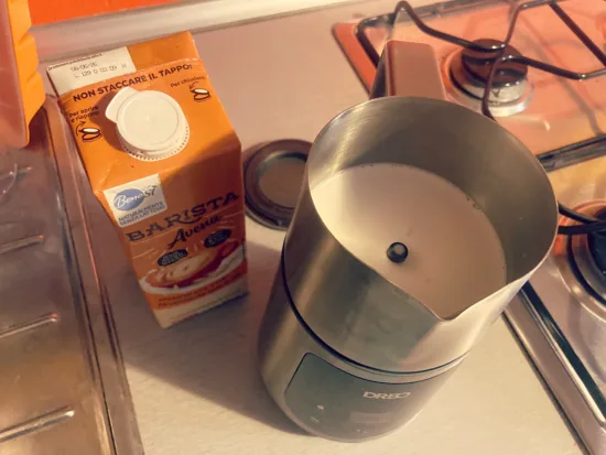 The DREO BaristaMaker next to a carton of almond milk.