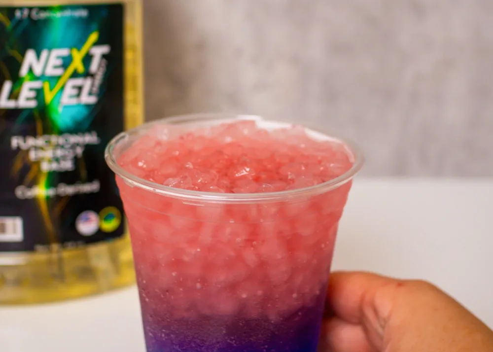 A strawberry blue raspberry layered energy drink in a plastic cup.