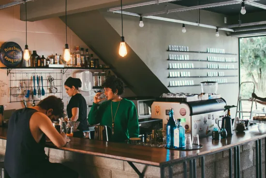 Two baristas work behind the espresso bar.