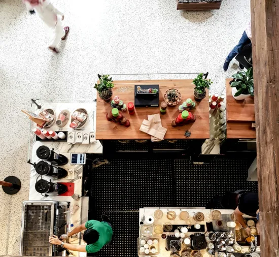 A view from above a cafe's espresso bar, with a barista working on the espresso machine.