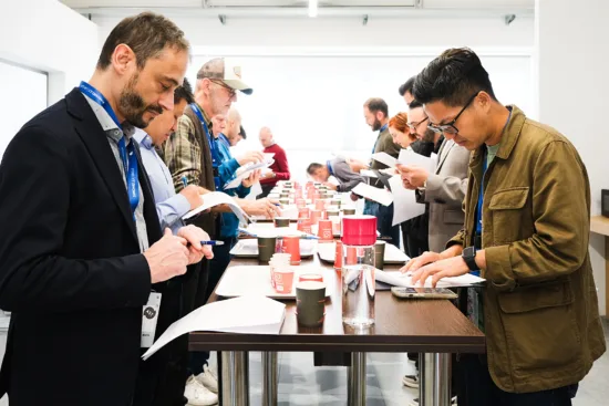 People at a long table looking over papers. Small red and black coffee cups sit in front of each.