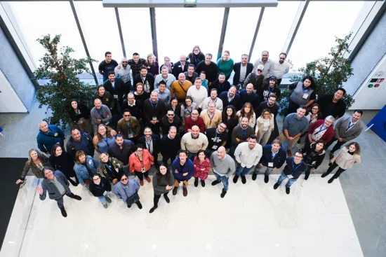 A large group of people gathered for a photo in front of windows.