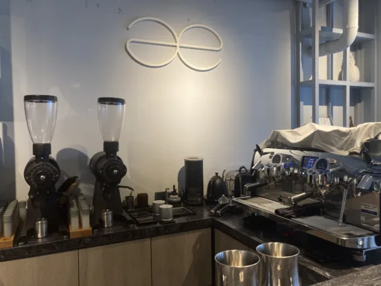 A coffee bar with æ's logo on the wall behind the counter.