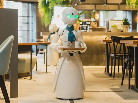 A humanoid robot carried two drinks on a tray inside a cafe.