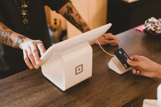 A customer taps a credit card on a Square system's card reader.