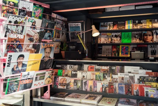 The walls of News & Coffee are lined with colorful magazines and books of all kinds, speakers, and a lamp.