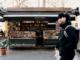 A passerby in headphones walks in front of News & Coffee stand.