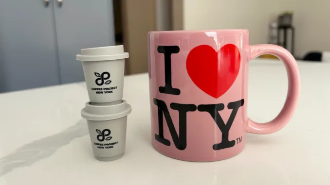 Two coffee pods stacked together next a pink I heart NY mug.