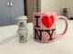 Two coffee pods stacked together next a pink I heart NY mug.