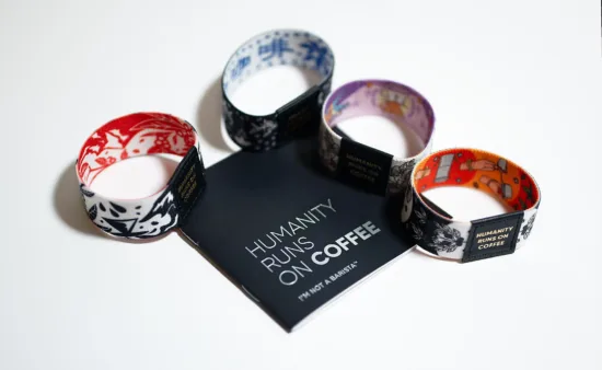 Four different wristbands with different colors and patterns. A middle label says Humanity Runs On Coffee.