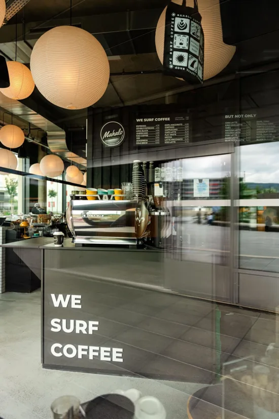 The inside of a Mahalo location with paper lanterns, black walls and bright coffee cups.