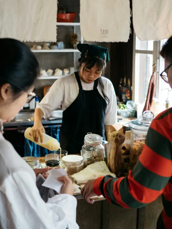 People preparing coffee in a home kitchen.